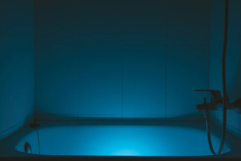 a deep tub lit by blue lighting in a bathroom