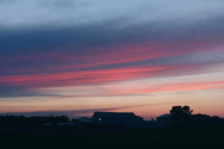 an airplane flying over a rural landscape during sunset