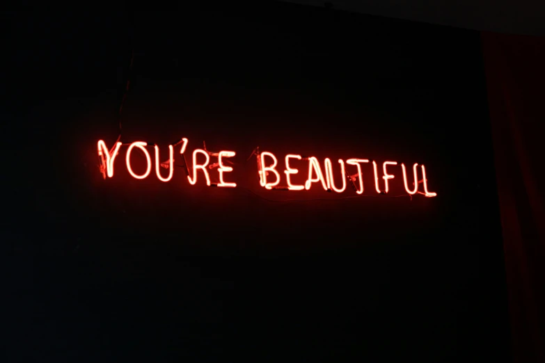 you're beautiful sign lit in the dark with a red light