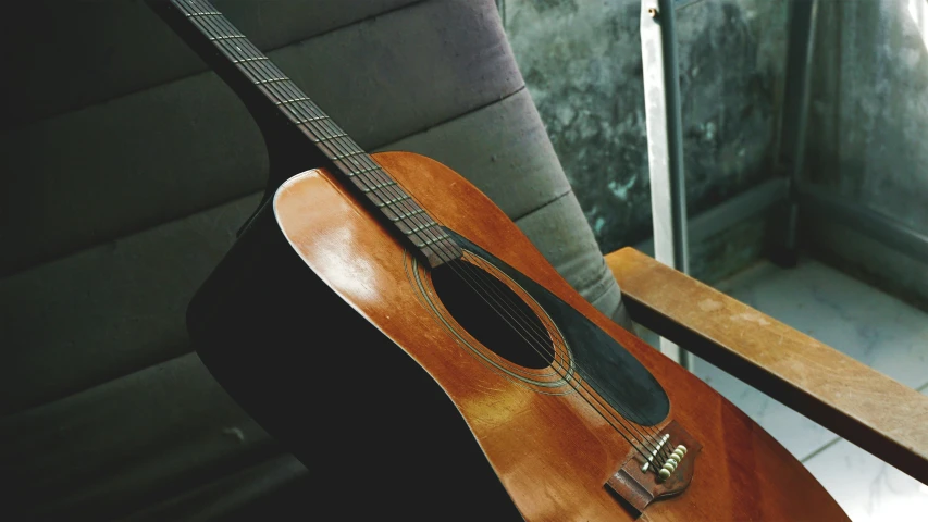 a guitar with the strings down laying on a bench