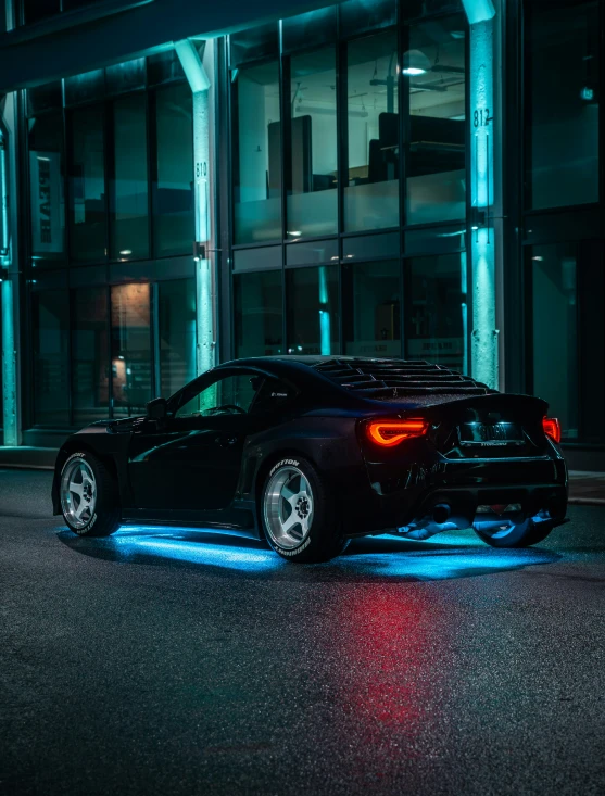 a black sports car parked in front of a very big building