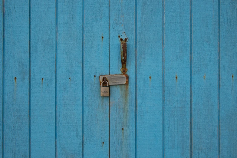 a metal padlock hangs on the side of a blue building