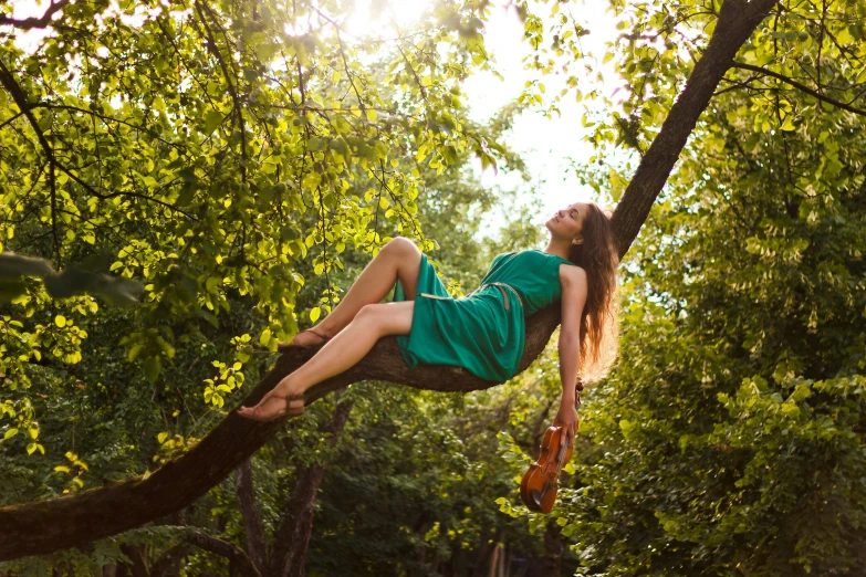 girl in a green dress lying in a tree