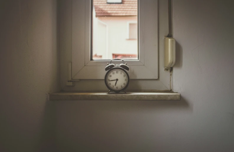 the small clock is on a window ledge in front of the window