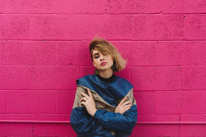 a girl leaning against a wall with her arms crossed