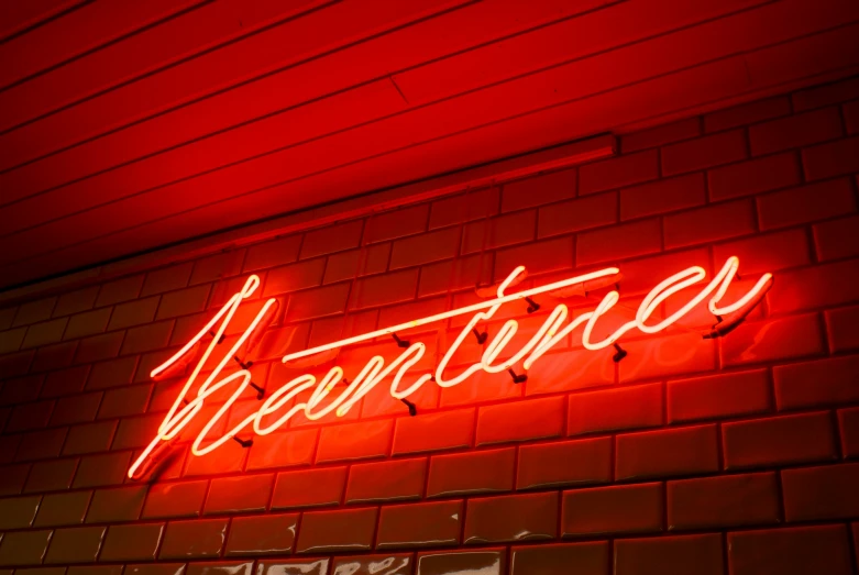 a neon sign hangs from the side of a brick building