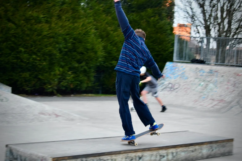 two men skateboard on the edge of a concrete ramp