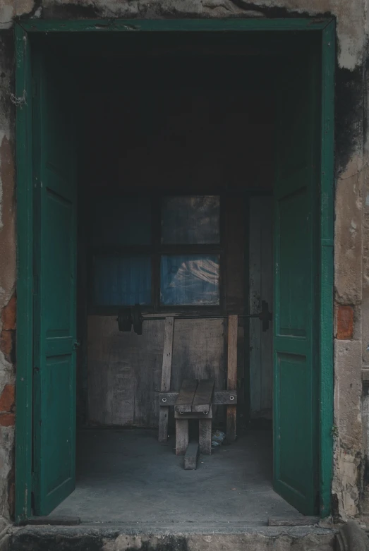 the open door to a green window next to a bench