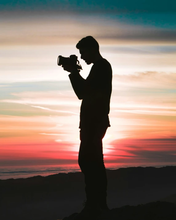 a man taking a po with a camera on top of a hill