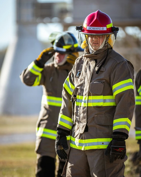 a group of firefighters standing on top of a grass covered field