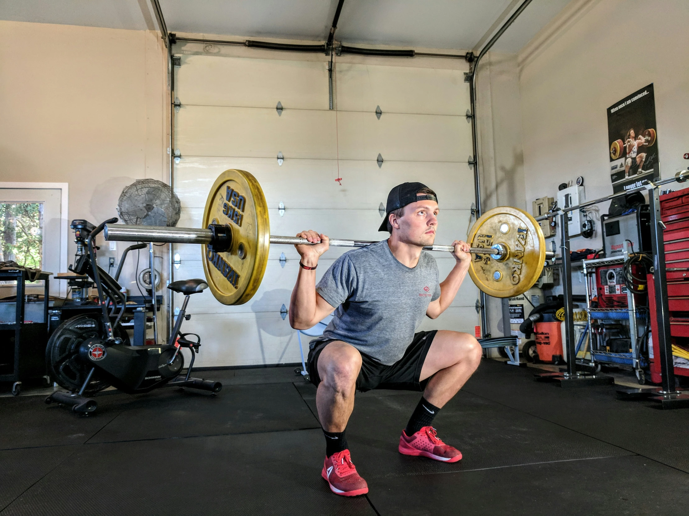 a man squatting down with his arms on the barbells