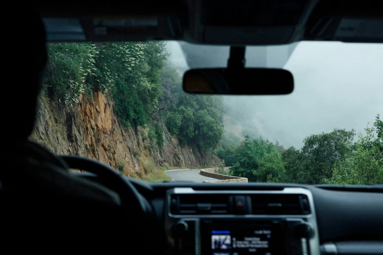 view from inside a vehicle on a narrow road and greenery