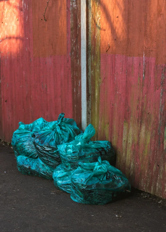 a bunch of bags of garbage near a wall