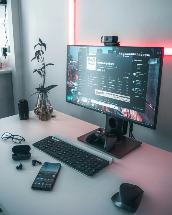 a desk with a computer, cellphone, and keyboard on it