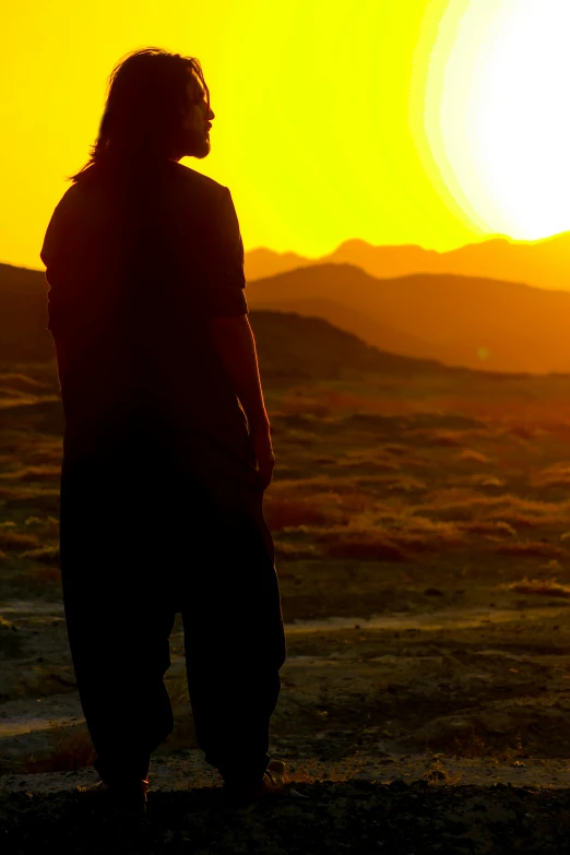 a man looks out over the desert at the sun