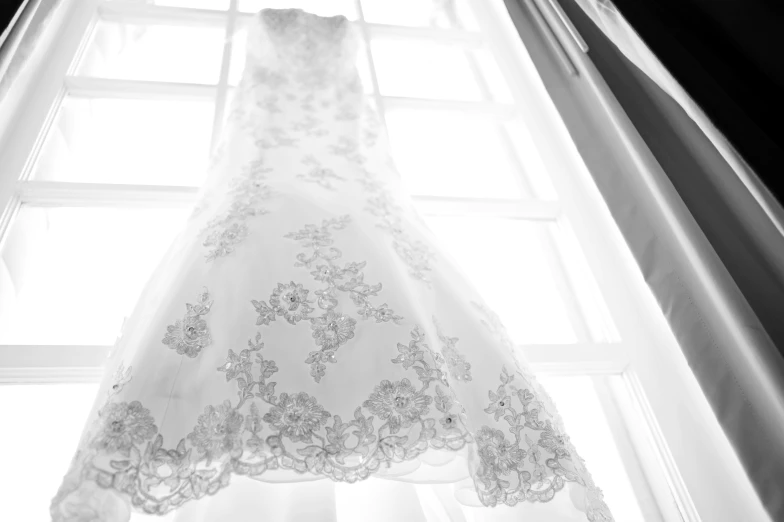 the wedding dress hangs from the window sill