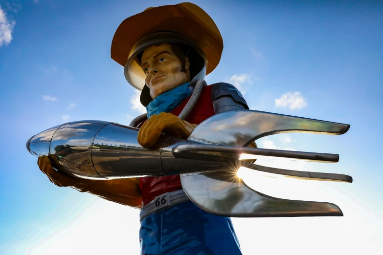 a tall metal statue holding a plastic object in its hands