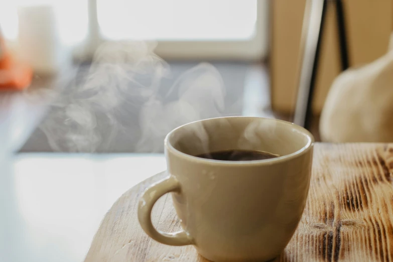 a coffee cup on a table with steam rising out of it