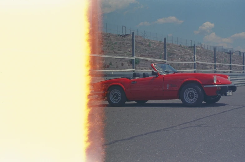 a red convertible car driving along the road