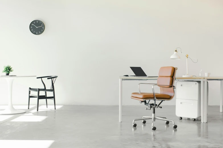 a clean white room with a desk, chair and clock