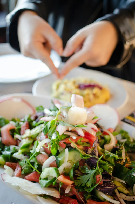 a person is setting a plate with salad on it