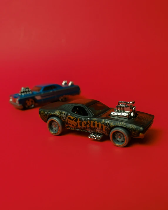 two toy cars that are sitting next to each other on a red surface