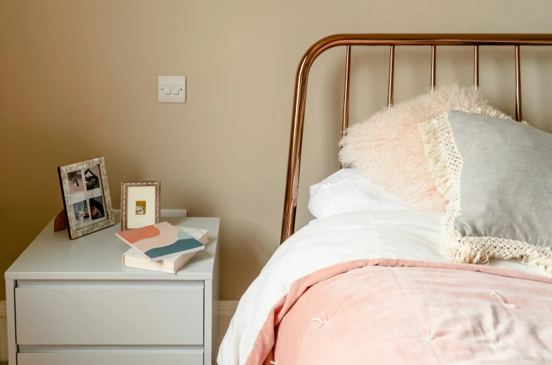 a white bed with a gold headboard and pink sheets