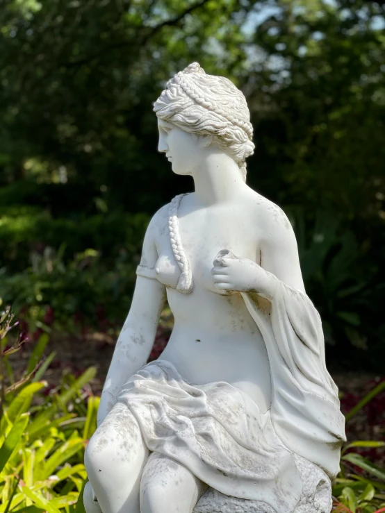 a statue of a seated woman surrounded by plants