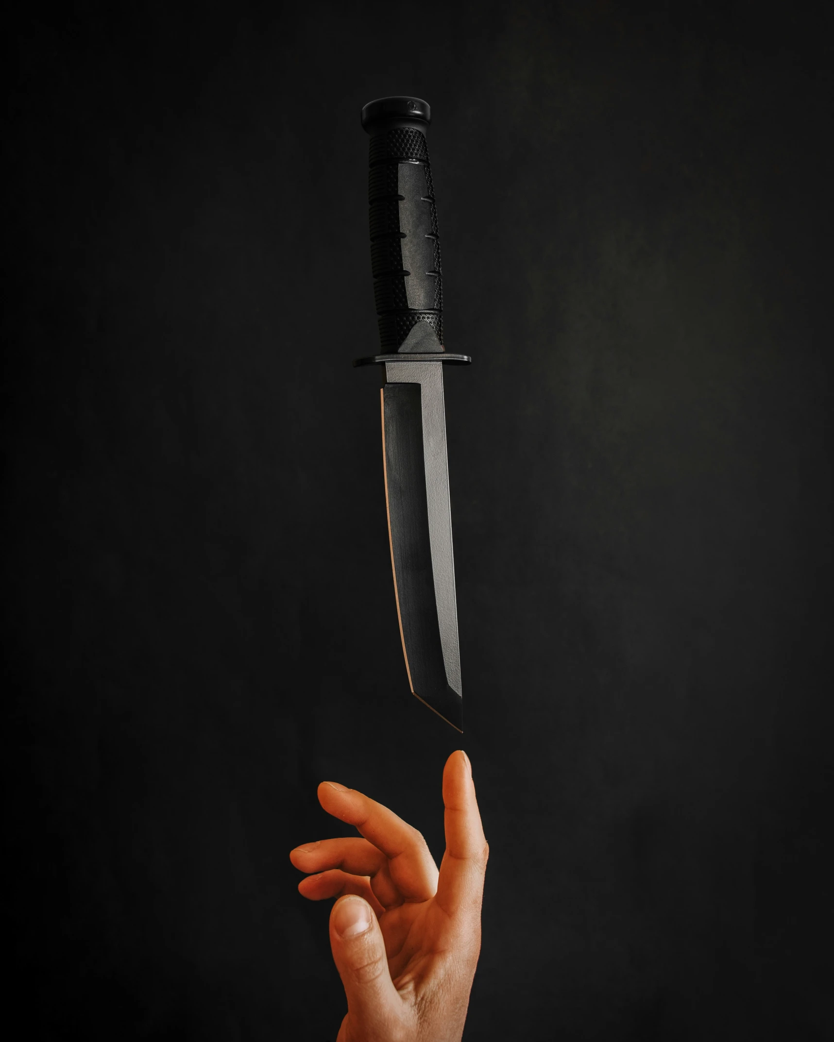 a person holding a big knife over a black background