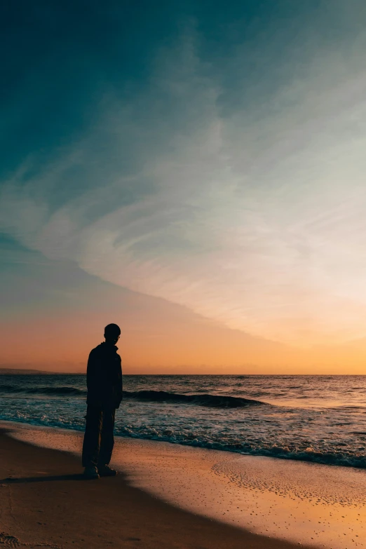 a man standing on the beach at sunset