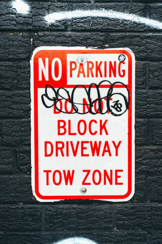 a parking sign indicating that no parking does not block driveway tow zone