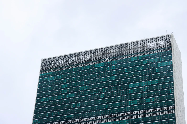 the green facade of a large building under a cloudy sky