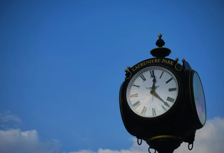 a black and white clock against the blue sky