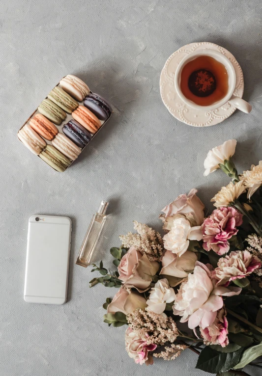 a table topped with flowers and macaroons next to a tea cup