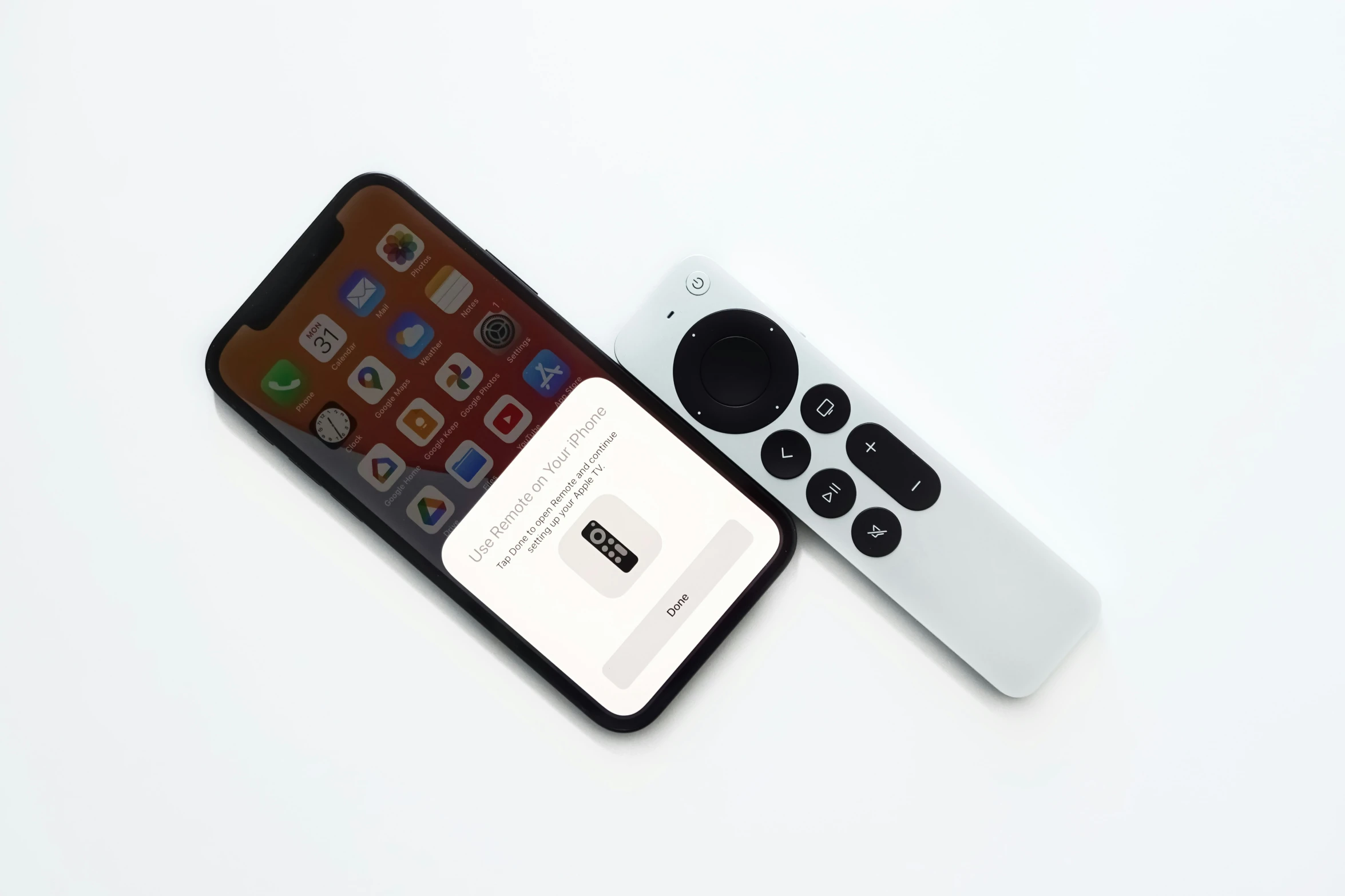 an iphone and a remote are sitting side by side