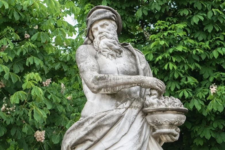 a statue that is in the grass next to a tree