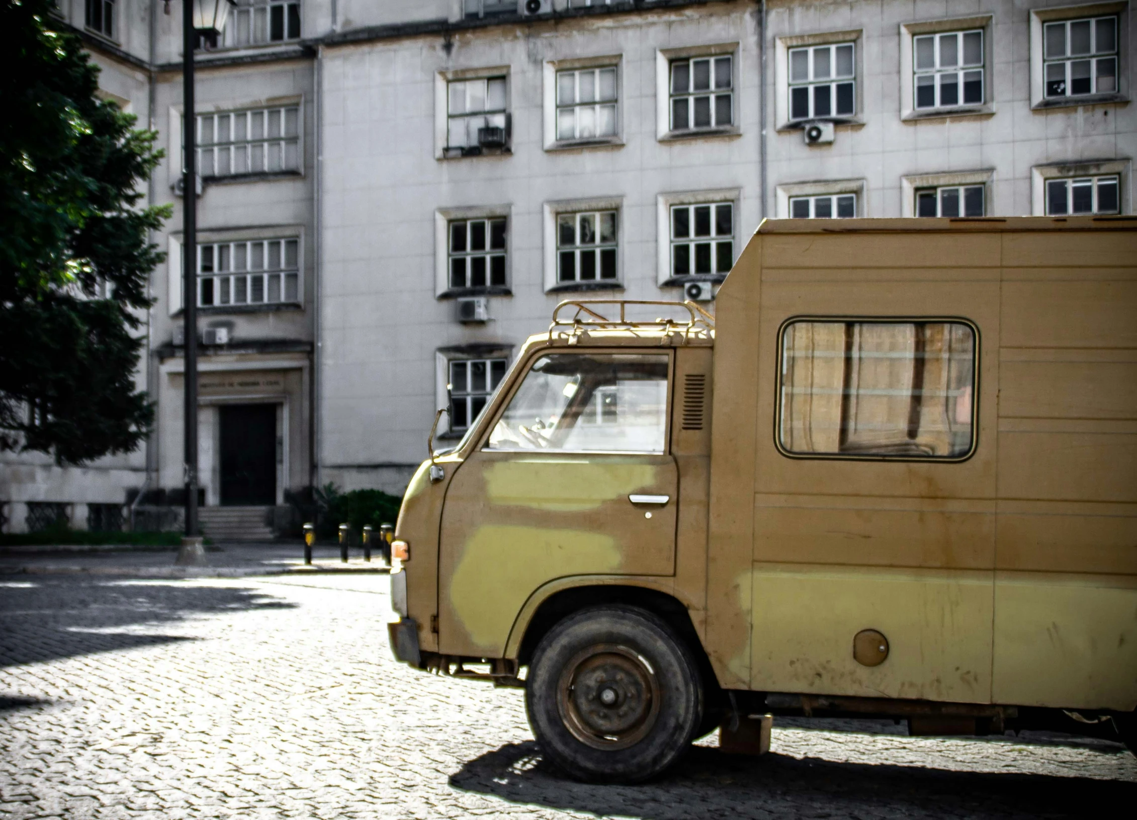 an old style small military van parked outside of a large building