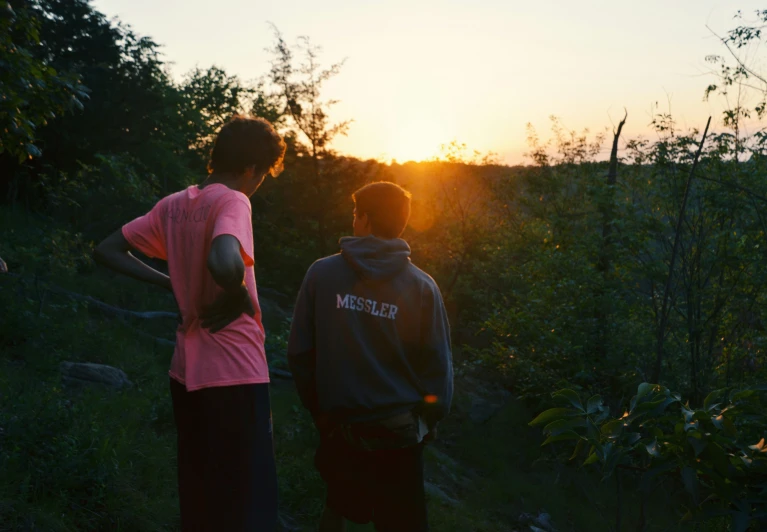 two people standing in a field at sunset