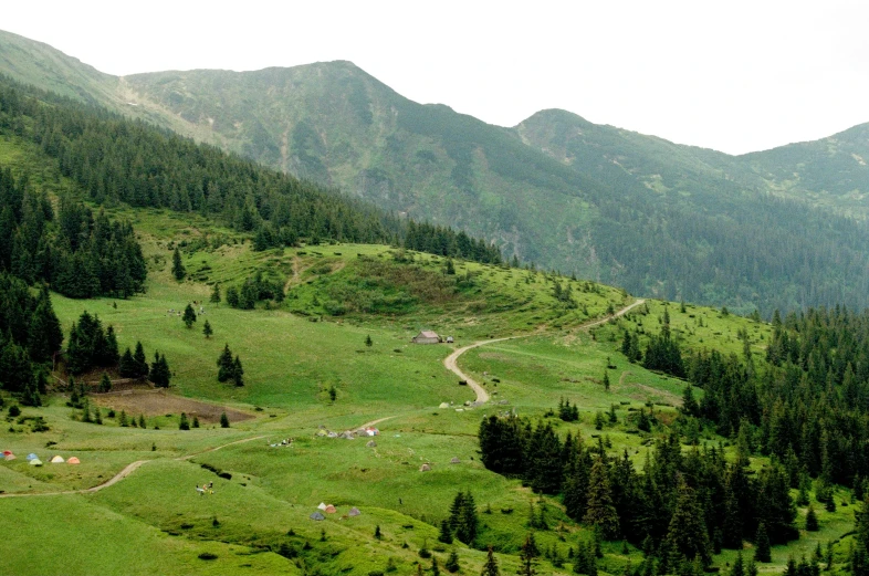 green hilly terrain on a cloudy day with mountains in the background