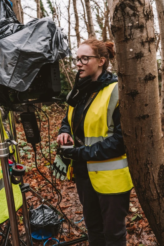 a woman stands next to a tree and has soing in her hand