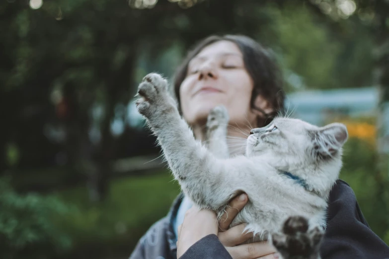 a lady holding a small white cat up to her face