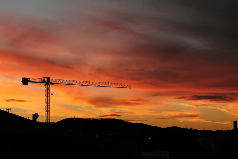 a tower crane on top of a building under a cloudy sky