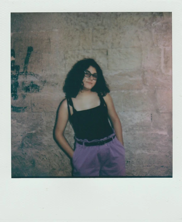 a woman wearing glasses is posing in front of a wall