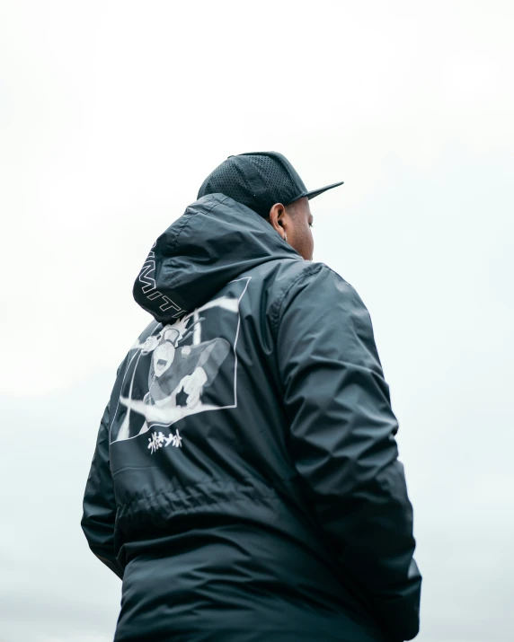 a man wearing a hat and jacket standing in the grass