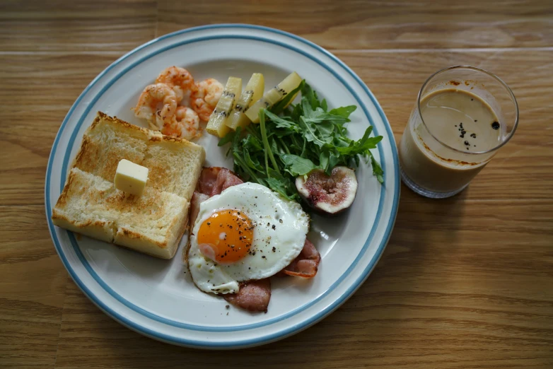 a plate with bacon, eggs, bread, and vegetables on it