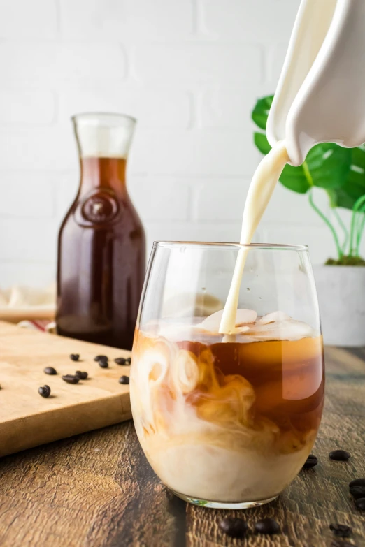 a pitcher pouring coffee into a glass on a wooden surface