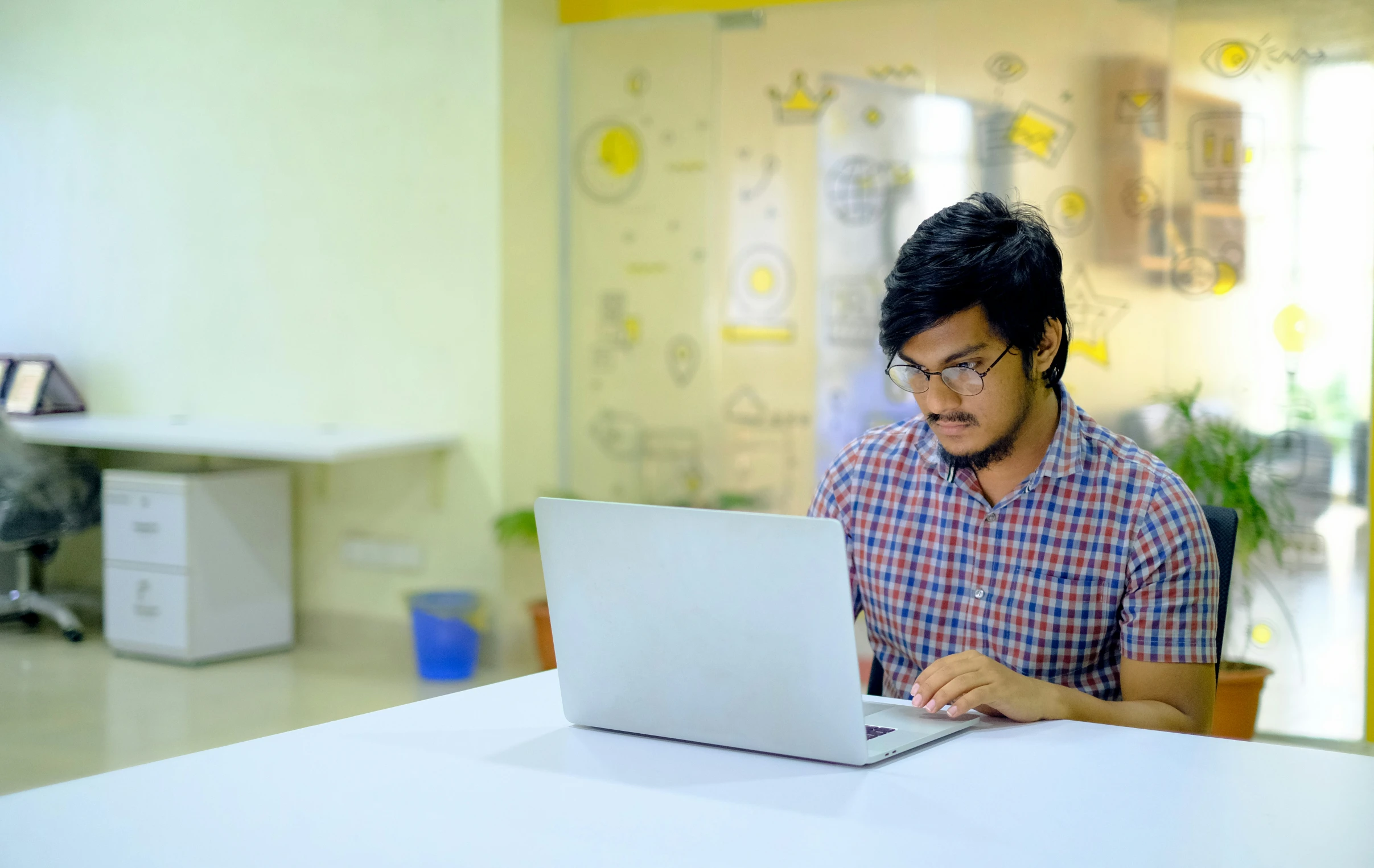 a man in plaid shirt using laptop at table