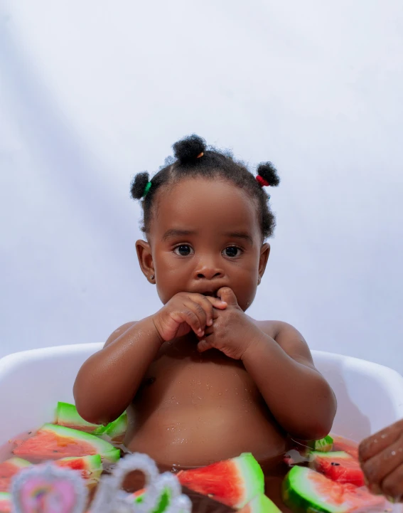 baby in a tub filled with watermelon slices