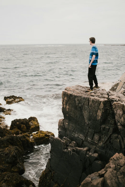 young male on the rocks overlooking the water