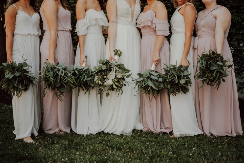 bridally women standing in the grass with their bouquets